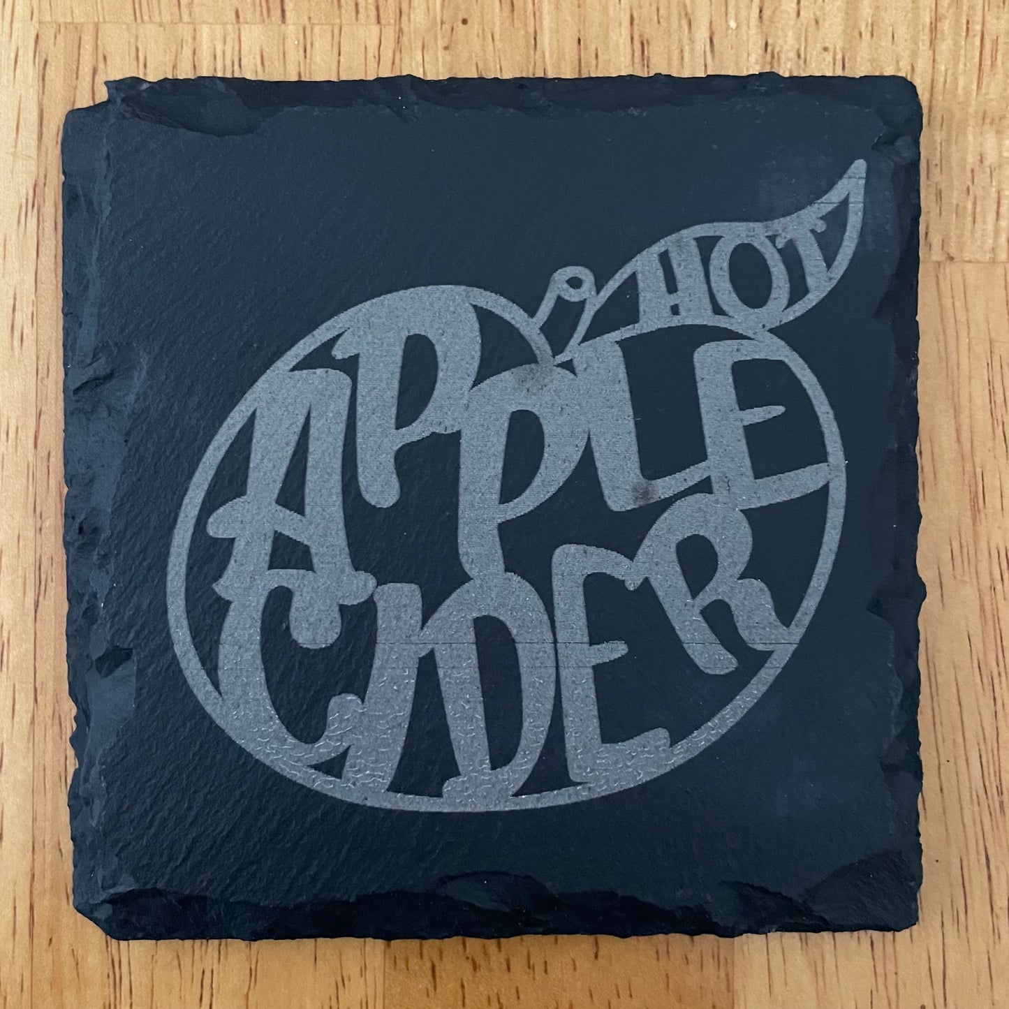Square black slate coaster laser engraved with hot apply cider text inside apple shape