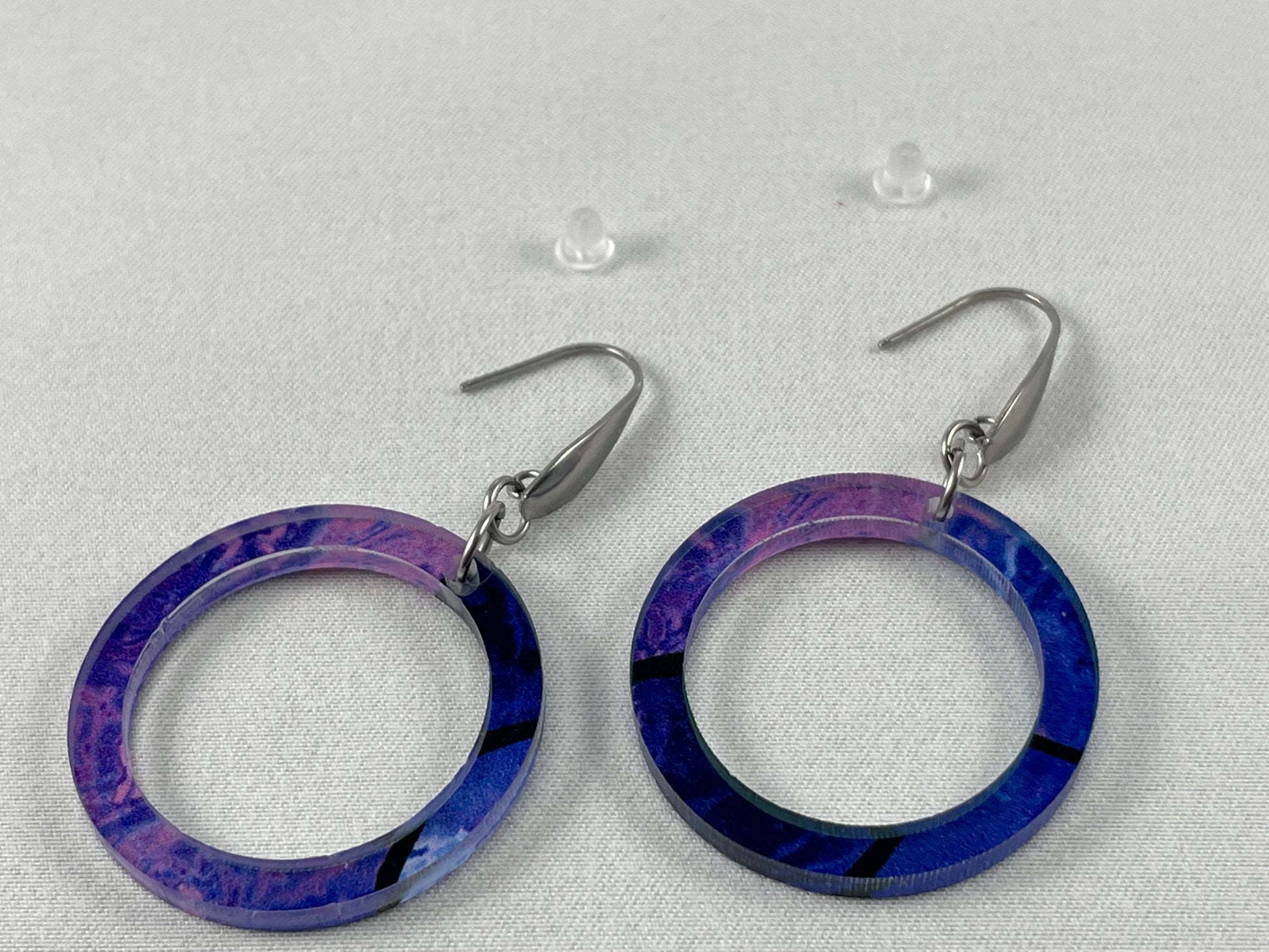 Detail view of Abstract purple round dangle acrylic earrings on stainless steel ear wires with teardrop accent and included silicone earring backs