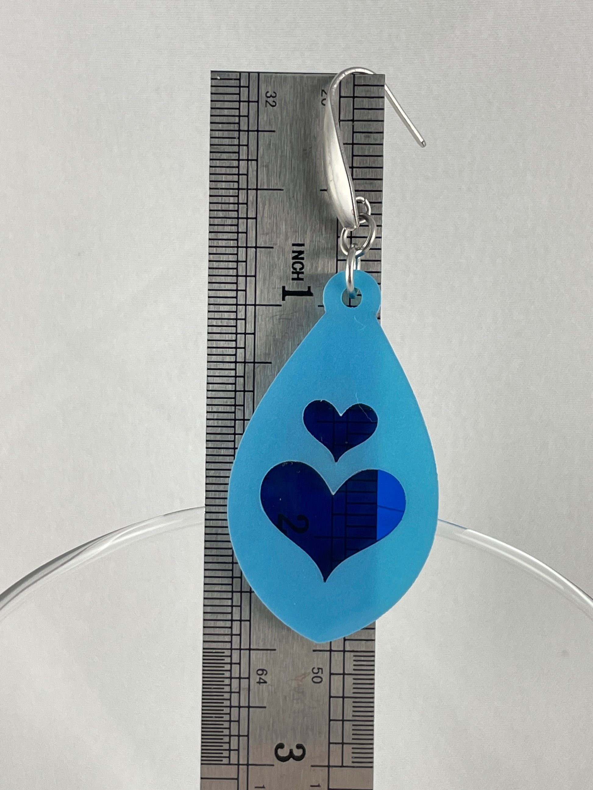 Size reference showing 2.5" drop length of light blue acrylic teardrop earrings with lapis blue inlay hearts on stainless steel ear wires with teardrop accent