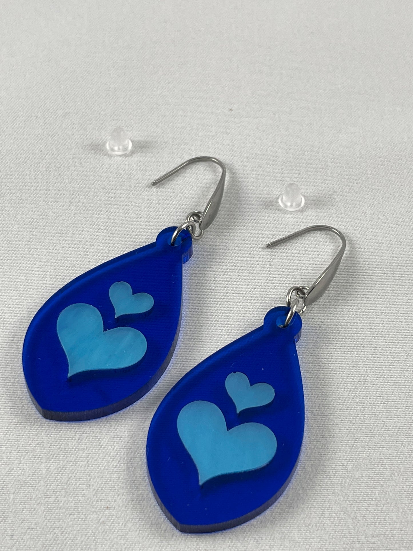 Lapis blue acrylic teardrop earrings with light blue inlay hearts on stainless steel ear wires with teardrop accent and included silicone earring backs