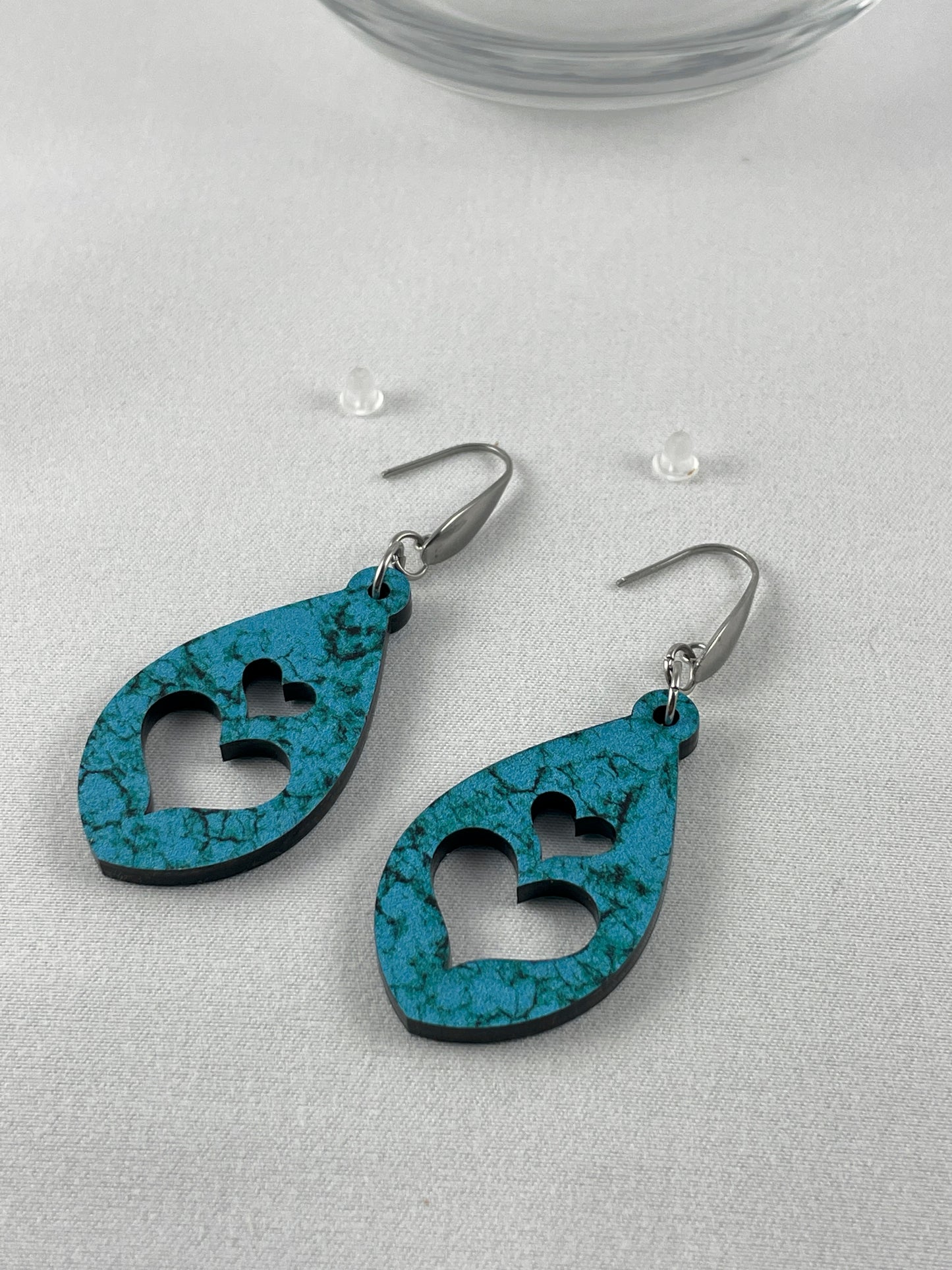 Detail view of Turquoise acrylic teardrop heart earrings with stainless steel ear wires with teardrop accent and included silicone earring backs