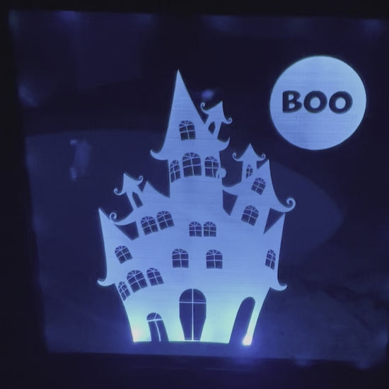 Video of haunted house engraved on mirror in shadow box frame illuminated with multicolor lights